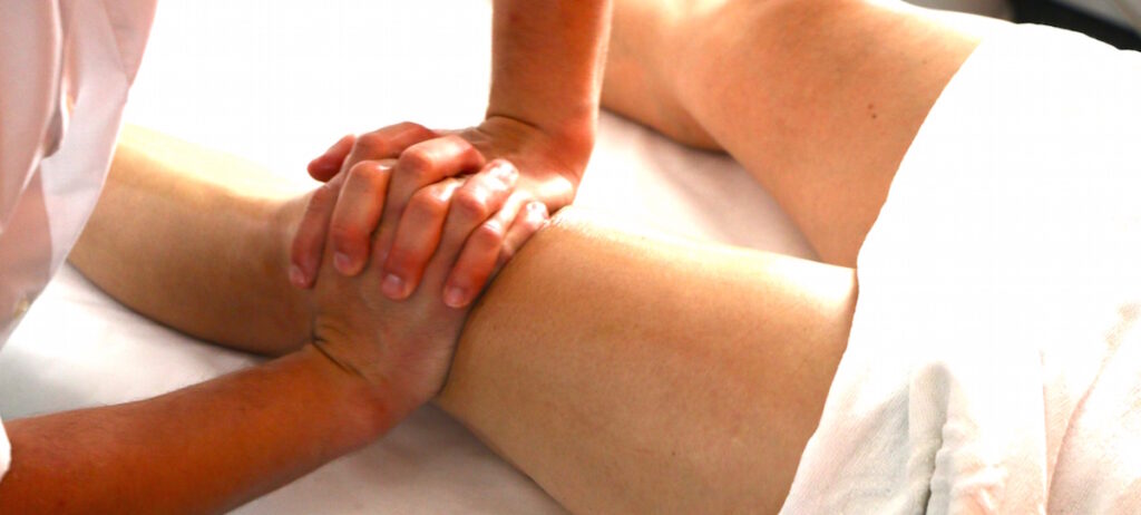 Massage sur la jambe d’un sportif, en phase de préparation à l’effort